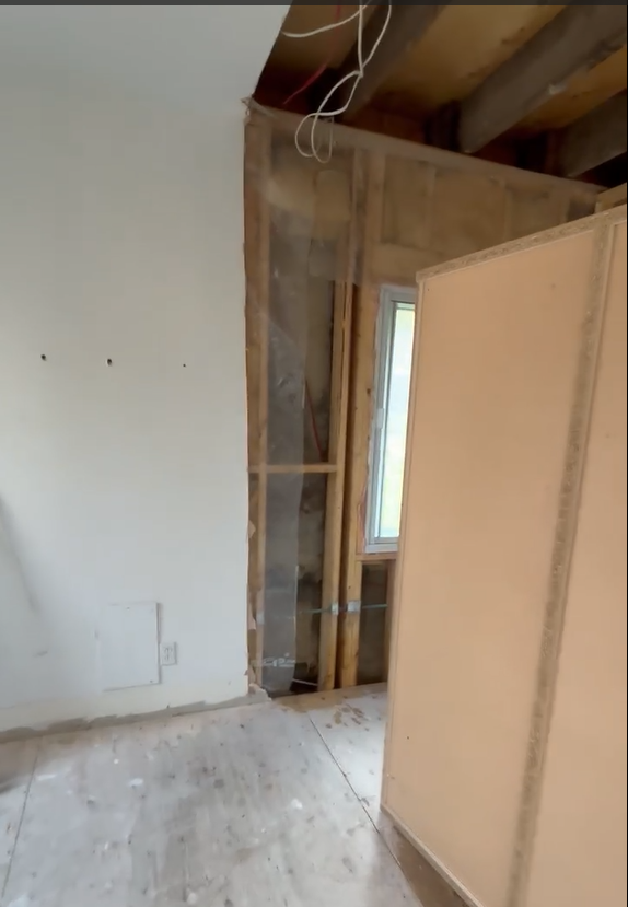 Gros plan sur une section de mur démolie avec précision, laissant l'ossature de bois et le câblage intacts. Le chantier est propre, illustrant une démolition sélective et soignée à l'intérieur d'une maison par AdréCo.